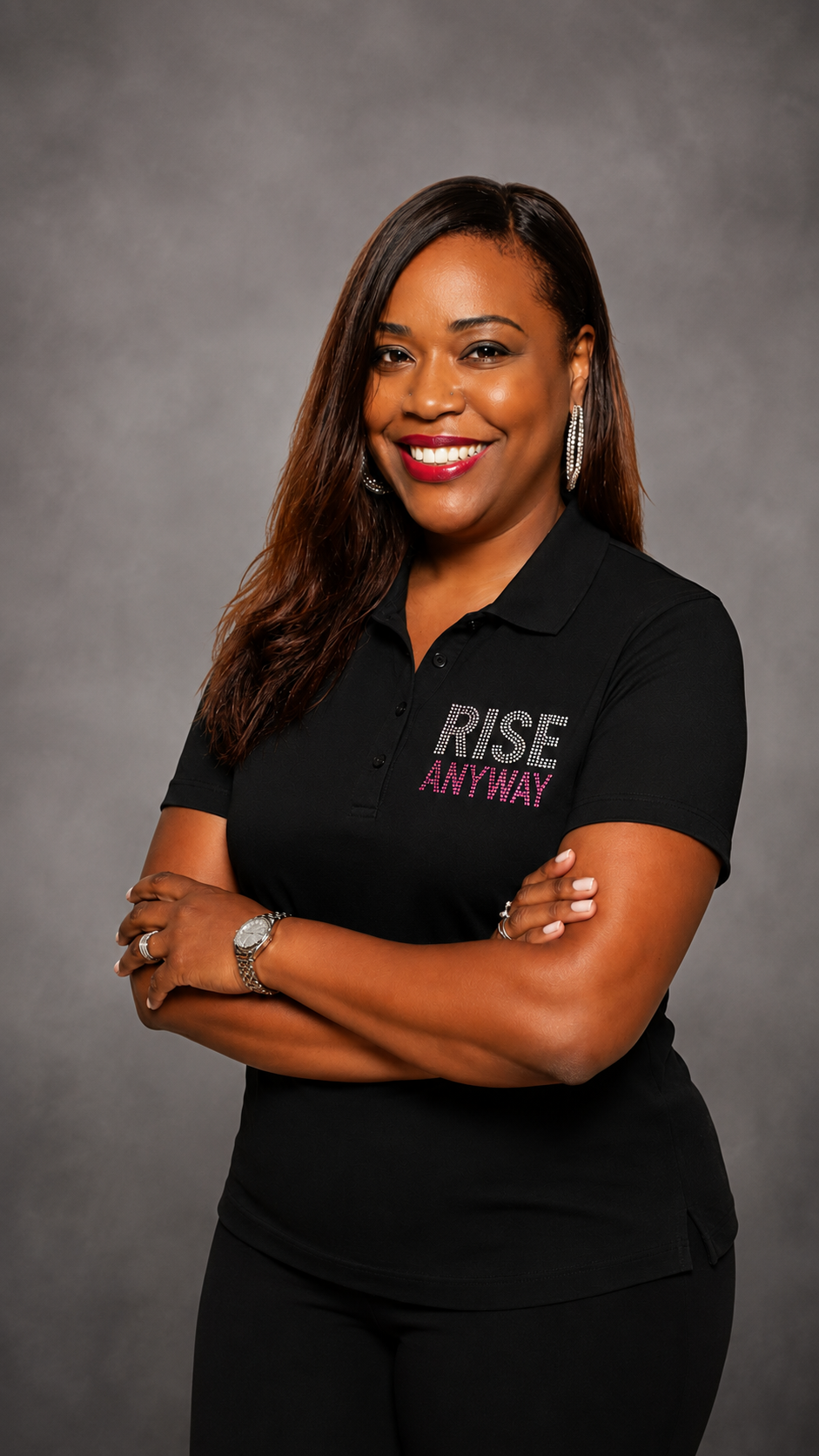 Stacy McDaniels, smiling with arms crossed in a black Rise Anyway polo